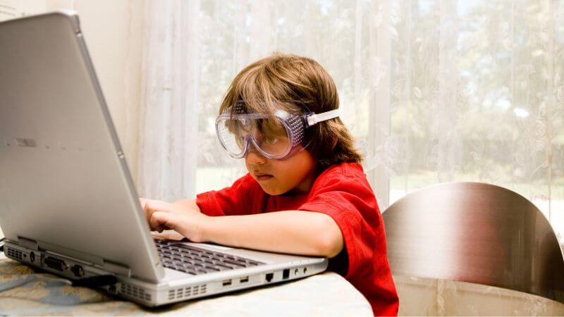 a child wearing goggles and using a laptop
